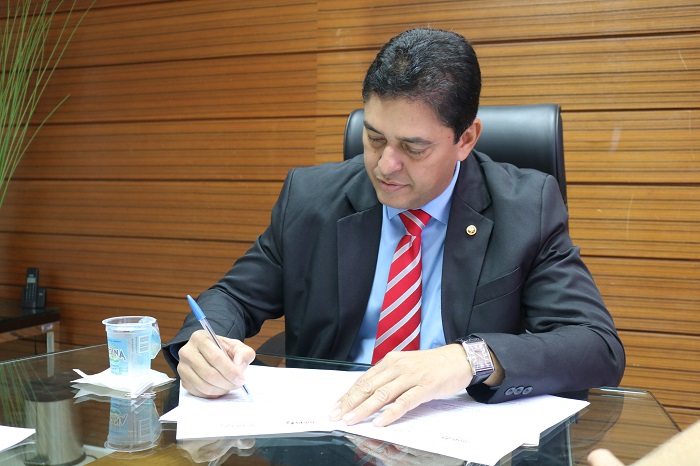 Homem sentado assinando um documento 