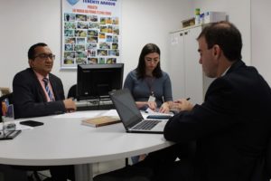 Três pessoas reunidas numa mesa durante reunião