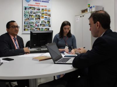 Três pessoas reunidas numa mesa durante reunião