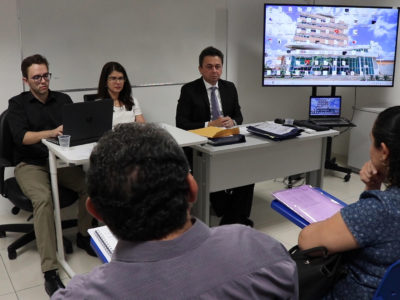 tres pessoas sentadas em uma mesa olhando para frente