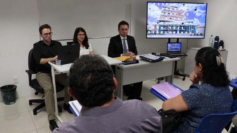 tres pessoas sentadas em uma mesa olhando para frente
