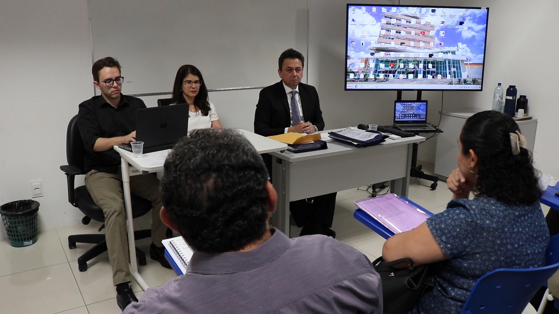 tres pessoas sentadas em uma mesa olhando para frente