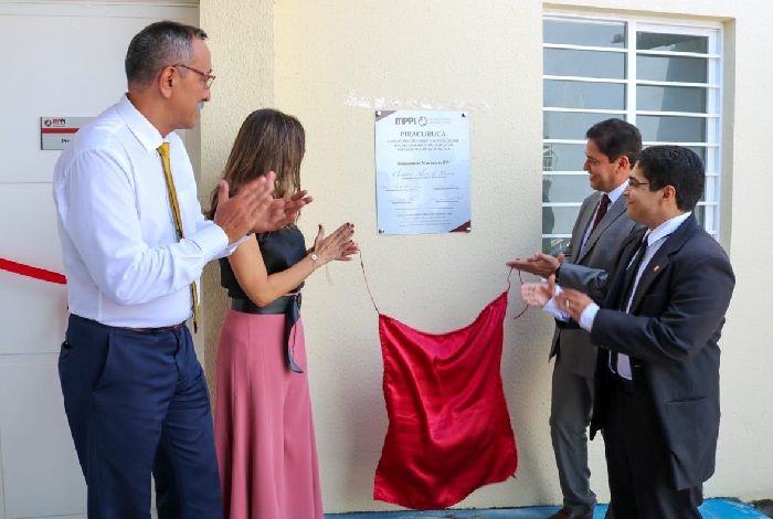 Pessoas de pé batendo palmas e olhando para uma placa 