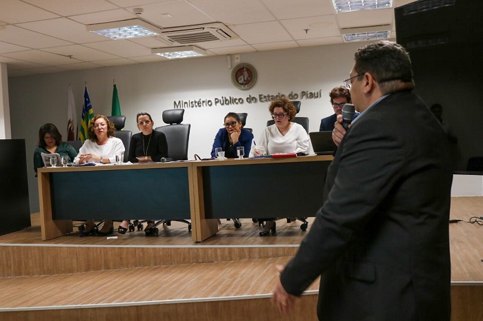 Pessoas sentadas olhando para outra que está de pé 