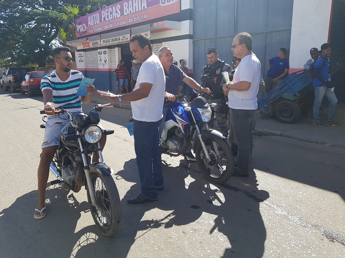 Pessoas entregando material educativo para motociclistas 