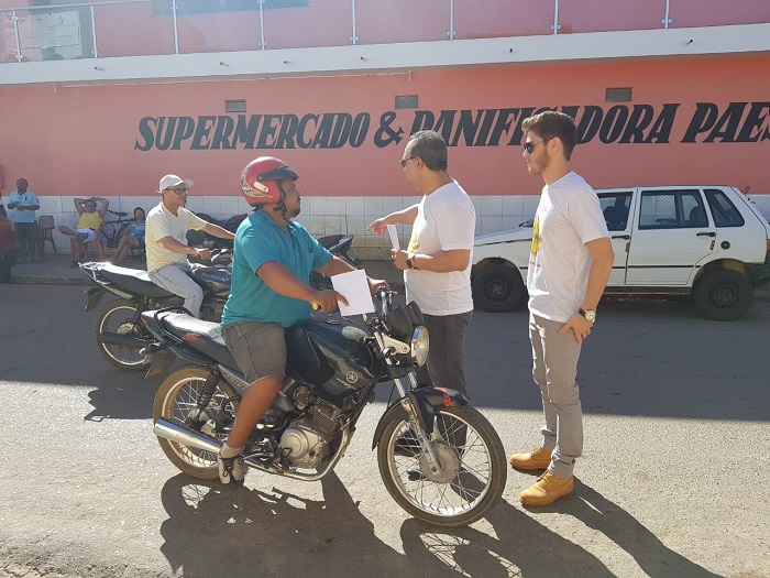 Pessoas entregando material educativo para motociclistas 