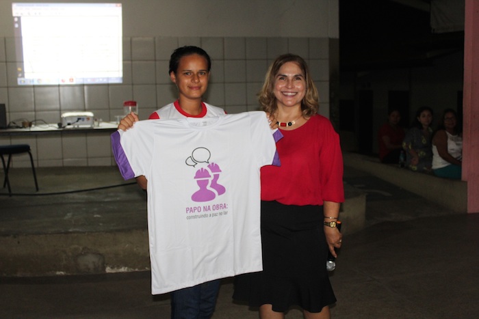 Promotora de Justiça entrega para estudante camiseta com a logomarca de projeto contra a violência doméstica