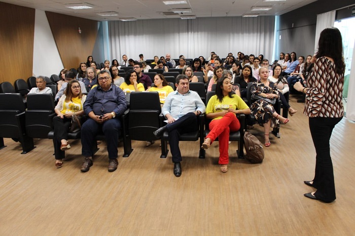Mulher falando para plateia de auditório 