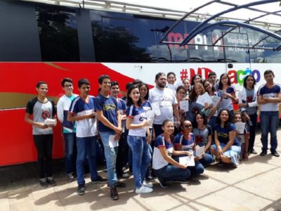 Estudantes posando para foto em frente ao ônibus do Procon Itinerante