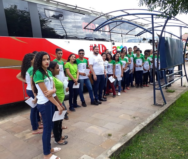 Estudantes posando para foto em frente ao ônibus do Procon Itinerante