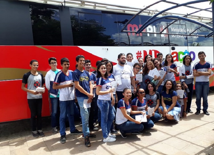 Estudantes posando para foto em frente ao ônibus do Procon Itinerante