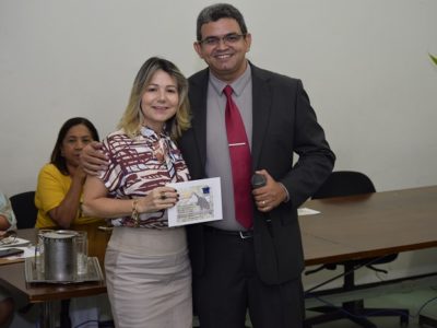 Duas pessoas de pé sorrindo segurando um certificado