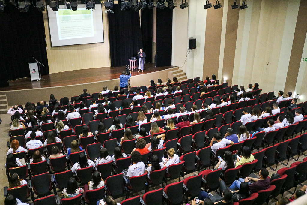 Estudantes observam slide exibido ao fundo da imagem
