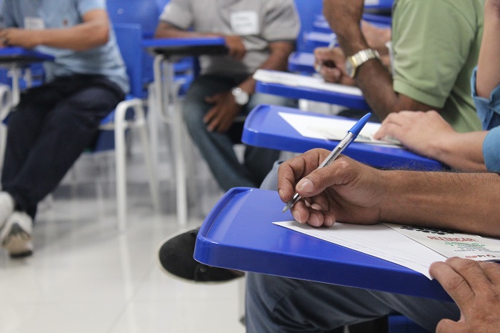 Pessoas sentadas em cadeiras escrevendo 