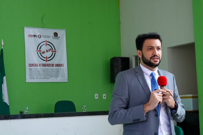 Homem de pé falando para  público que o observa 