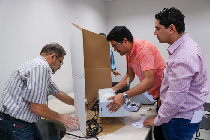Pessoas manuseando urna eletrônica