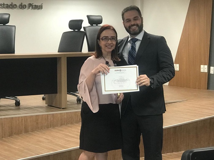 Pessoas de pé sorrindo segurando um papel nas mãos 