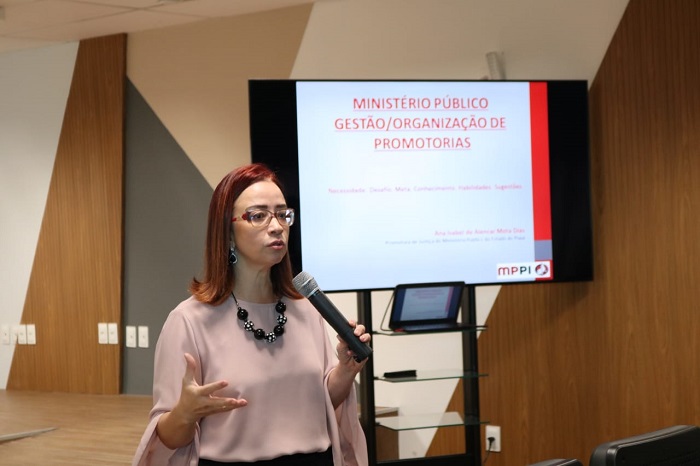 Pessoa de pé falando com microfone nas mãos 