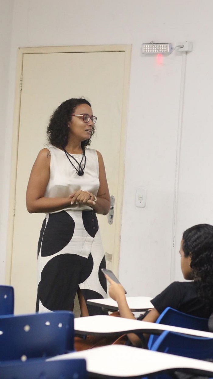 Mulher falando para plateia de sala de aula