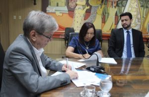 Pessoas sentadas assinando documento