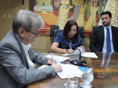 Pessoas sentadas assinando documento