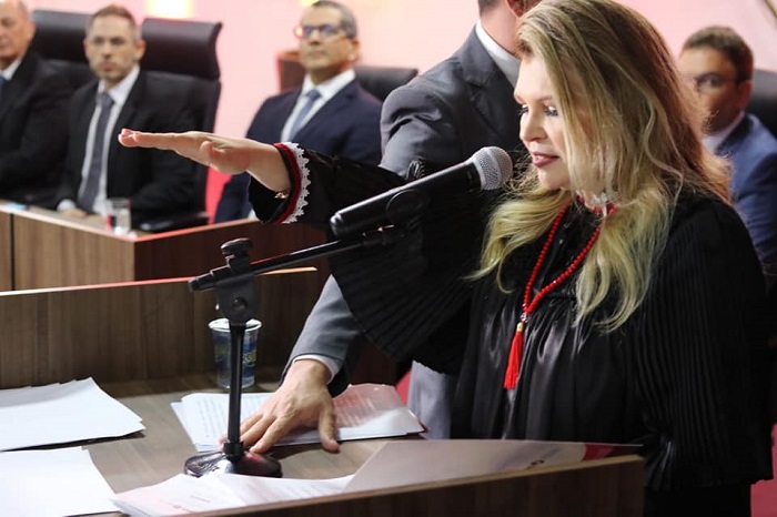 Mulher falando para público diante de plateia