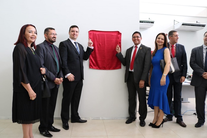 Pessoas de pé ao lado de uma placa de inauguração 
