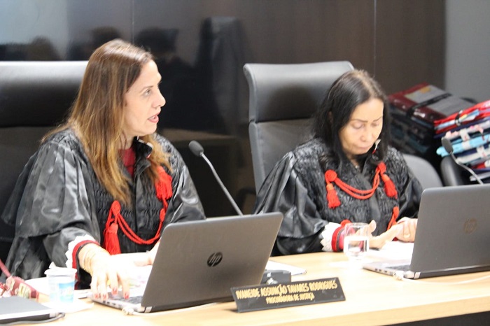 Pessoas sentadas atrás de uma bancada 