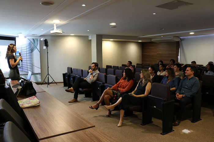 Mulher falando para plateia de auditório 