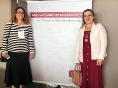 Duas pessoas de pé ao lado de um banner