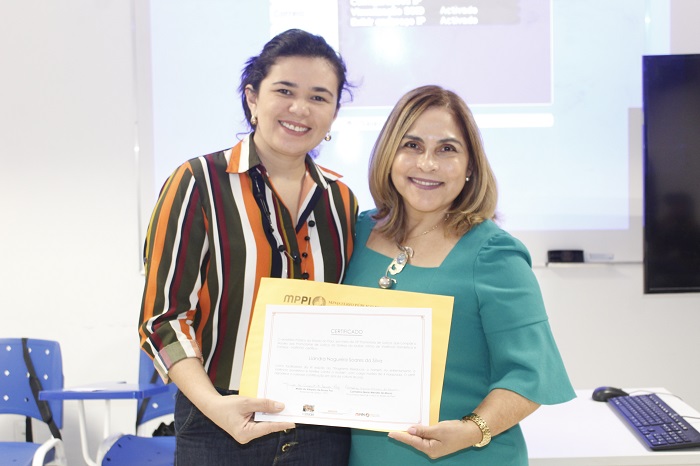 Pessoas de pé sorrindo e segurando um certificado 