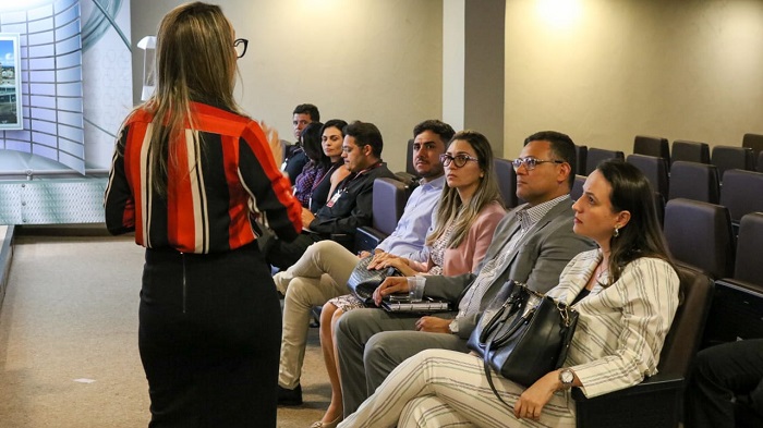 Pessoas sentadas observando mulher de pé falando 