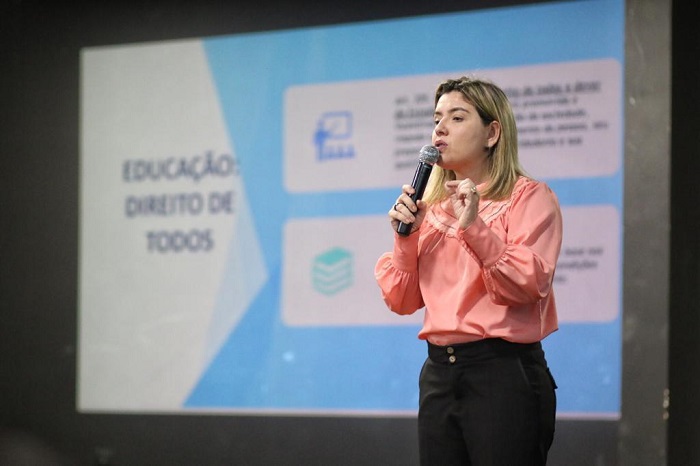 Mulher falando para público diante de plateia