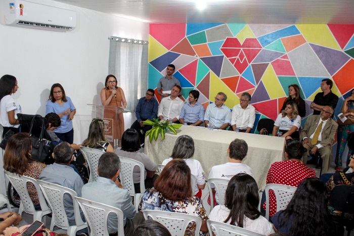 Mulher falando para público diante de plateia