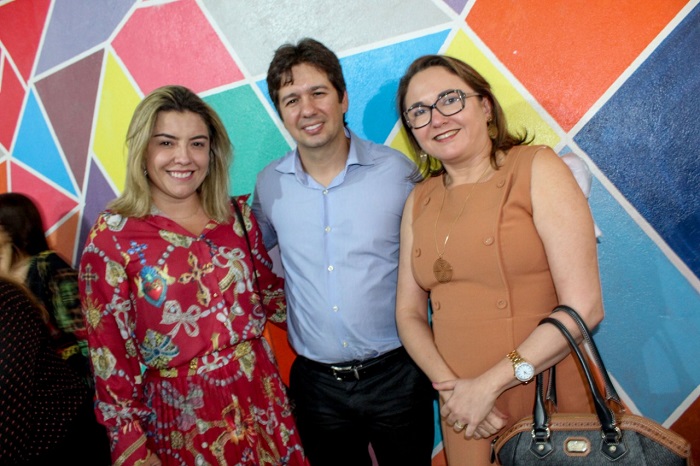 Duas mulheres e um homem sorrindo e posando para foto
