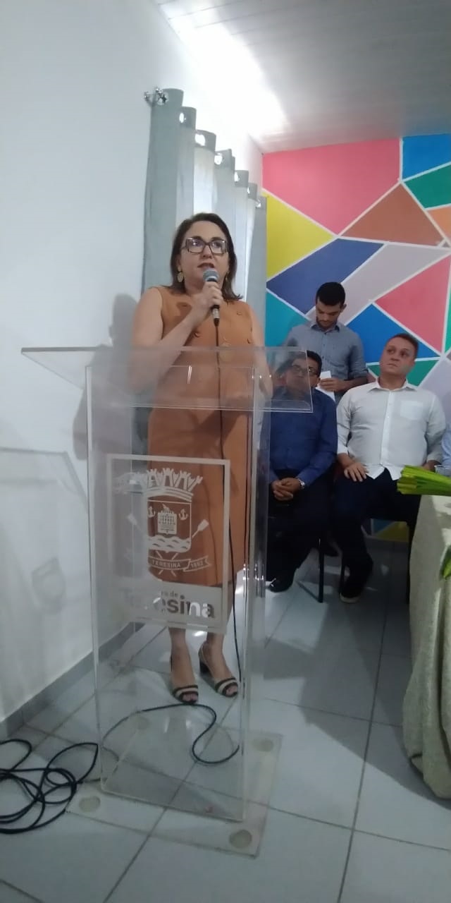 Mulher falando para público diante de plateia