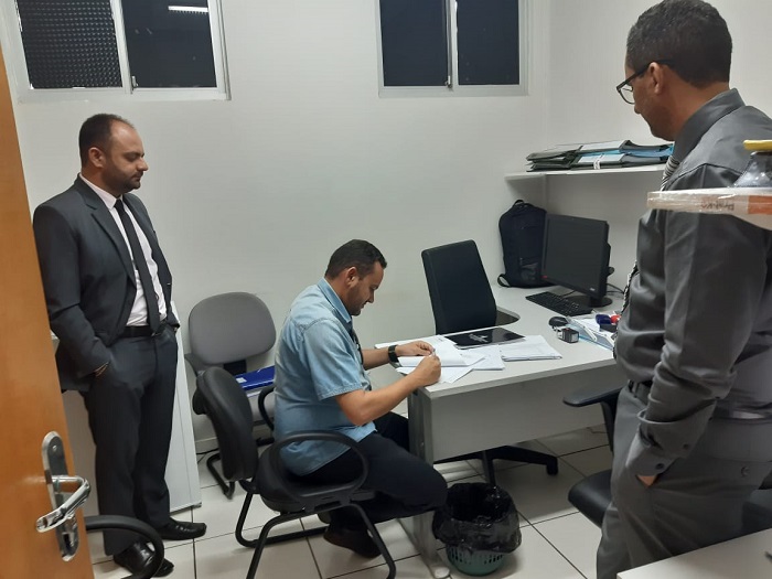 Pessoas sentadas assinando um documento