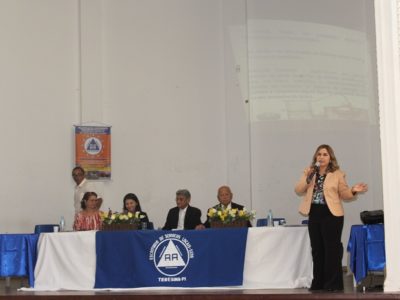 Mulher de pé falando pessoas que estão a sua frente