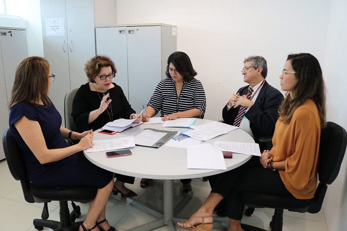 Pessoas sentadas em volta de uma mesa conversando entre si 