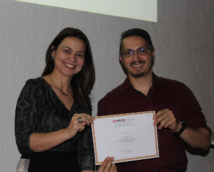 Pessoa sorrindo e segurando um certificado 