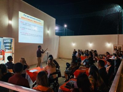 Pessoas sentadas em área aberta assistindo palestra