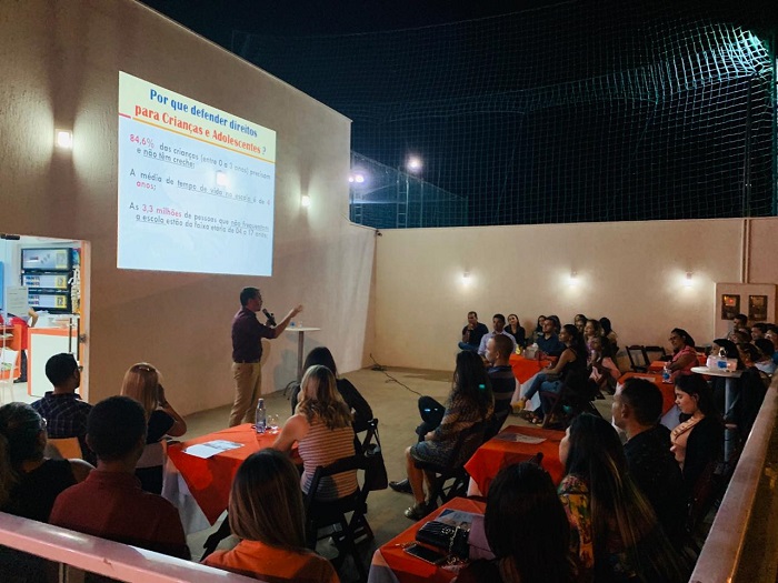 Pessoas sentadas em área aberta assistindo palestra