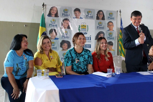 Pessoas reunidas em uma mesa de honra durante solenidade