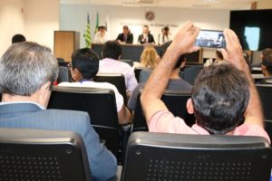 Pessoa com celular na mão registrando audiência pública