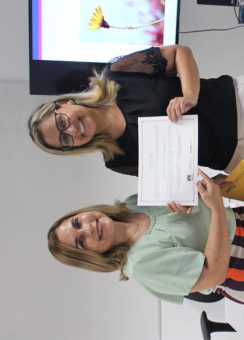 Pessoas de pé sorrindo e segurando um certificado 