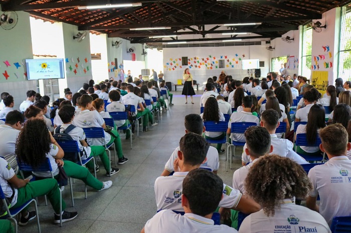 Pessoas sentadas em amplo pátio 