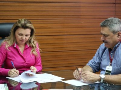 Mulher assinando documento e homem observando o gesto