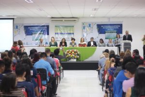 Pessoas reunidas num auditório diante de mesa de honra