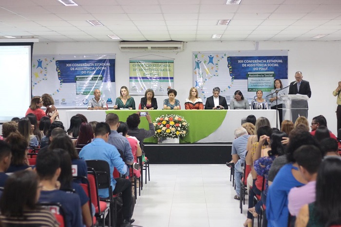 Pessoas reunidas num auditório diante de mesa de honra