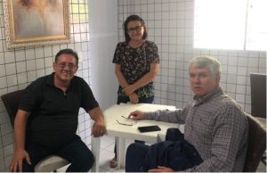 Dois homens sentados e uma mulher em pé